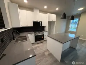 Kitchen looking back towards the front door with view of eating area and island with room for bar seating
