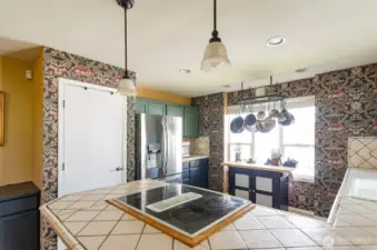 Another view of the kitchen showing pantry and added built-in cabinetry on either side. Pendant lights over downdraft stove.
