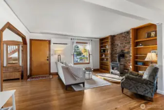 “Spacious living room with cozy gas stove, crown molding, and wood-wrapped windows.”