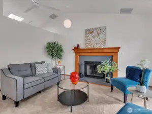 Living area with new carpet, vaulted ceilings, fireplace, and ceiling fan.