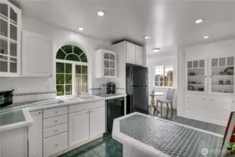Bright kitchen featuring an arched window over the sink and classic tile countertops.