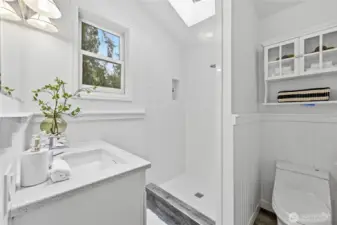 The skylight and window fill the primary bathroom with natural light.