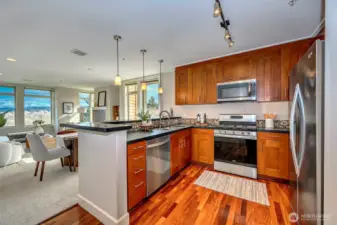 A beautifully appointed gourmet kitchen showcases stunning views of Mt. Baker, wrapped in rich cherry cabinetry, gleaming granite counters, warm wood flooring, and sleek stainless-steel appliances.