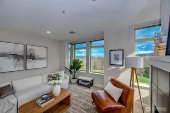 Sun-drenched living room with sparkling Puget Sound views and a warm, cozy gas fireplace.