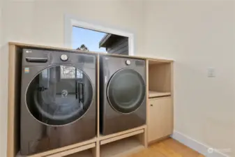 Laundry with built in cabinetry, complete with pull out tables to put laundry basket.