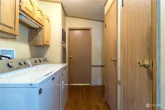 Utility area with laundry, H20 heater and storage closets, leading to 3/4 guest bath beyond