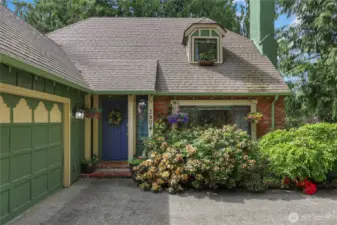 Enchanting Tudor-style entry surrounded by lush landscaping and a storybook setting.