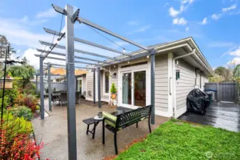 Patio with three pergolas and canvas covers and a barbecue deck at right alongside the townhome