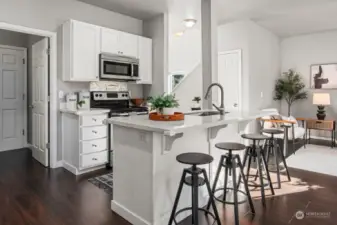 Open kitchen on the main floor with quartz counter tops and stainless steel appliances