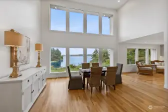 The living space on the main level with its' high ceilings and wall of windows looking to the north. To the right is the kitchen. The home has been fully remodeled.
