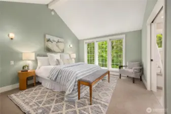 Upstairs, the primary bedroom features vaulted ceilings and large windows.