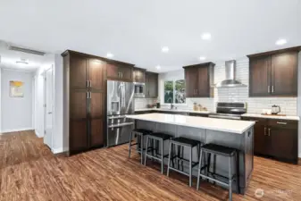 ??? Stunning Chef’s Kitchen – Modern, Spacious & Inviting!  This beautifully remodeled kitchen is the heart of the home, featuring rich espresso cabinetry, sleek quartz countertops, and a full-height subway tile backsplash for a timeless touch. Stainless steel appliances, including a French-door refrigerator and a vented hood, combine style with function. The oversized island with bar seating is perfect for entertaining or casual dining. Recessed lighting and wide-plank flooring complete the space, offering warmth and elegance in every detail.
