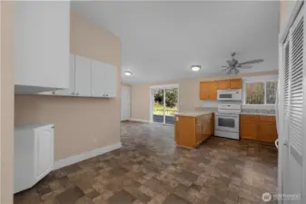 View from entryway towards your open-concept kitchen - also vaulted. Slatted doors to right house washer and dryer and your newer water heater. Kitchen nook to left houses tons of additional built in storage and provides space for an eat in kitchen set up. All appliances stay with home.