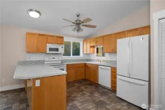 Close up view of open-concept kitchen with large peninsula and plenty of entertaining and counter space. Plenty of storage cabinetry and natural light. All appliances stay with home.