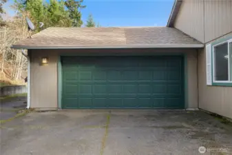 View of attached 2 car garage with additional storage space. Fresh exterior paint and newer roof. Your well housing lies to left of garage. Notice additional RV concrete pad parking directly to left as well. Tons of parking on property.