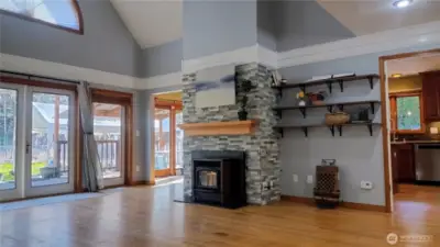 Living room with hardwood floors and glass doors leading to deck and backyard.