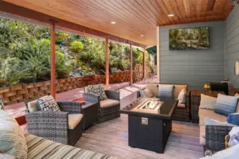 The wrap-around deck is flanked by lush, native greenery.