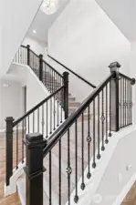 Elegant Stairwell with Wrought Iron Railing and Stunning Chandelier at the Top.