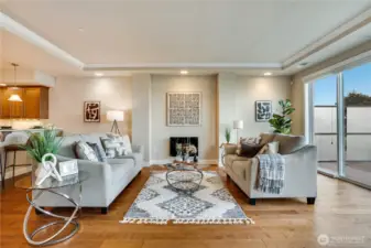 Sophisticated yet inviting, this light-filled living room showcases classic crown molding, a cozy gas fireplace, and golden hardwoods that glow beneath the Sound’s shifting skies.