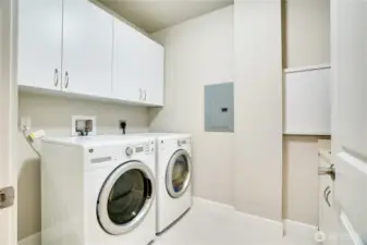 This expansive utility room combines function and sophistication, featuring premium washer and dryer units framed by generous wall-mounted cabinetry—ideal for keeping essentials neatly tucked away while maintaining a clean, streamlined aesthetic.