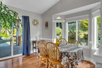 Dining space with large windows overlooking the backyard and sliding doors to the covered deck. Perfect for enjoying meals with plenty of natural light and scenic views.