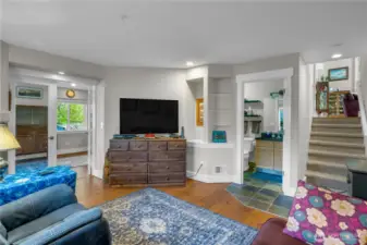 Cozy space featuring wood-style flooring, built-in shelving, and convenient access to a bathroom and additional room. Perfect for a media room, guest suite, or cozy retreat.