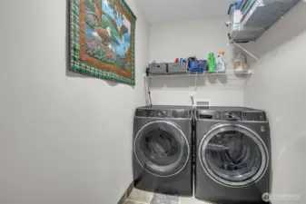 Efficient laundry space with modern front-load washer and dryer, tile flooring, and convenient shelving for storage and organization.