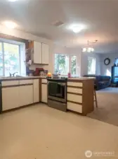 The kitchen opens seamlessly to the dining and living areas, creating a bright and welcoming space with large windows that bring in the beauty of the surrounding trees. With plenty of cabinet storage and an open layout, this heart-of-the-home design makes everyday living and entertaining feel comfortable and connected.