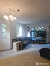 The living room offers a comfortable, light-filled space with large windows that bring in the surrounding greenery. The open layout provides plenty of room for relaxing or entertaining, creating a cozy centerpiece for everyday living.