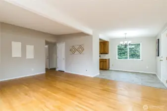 Living room connects to the dining area and kitchen. Door on the right opens to the attached garage.