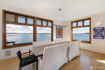 Elegant dining area framed by expansive windows, offering panoramic waterfront views—an exceptional setting for everyday dining and entertaining on San Juan Island.