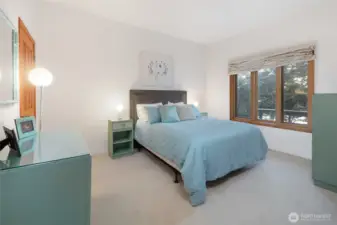 Bright and inviting guest bedroom with soft natural light and tranquil outlooks, offering comfort and privacy for visitors.