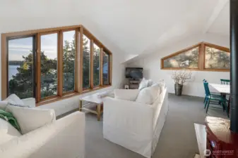 Light-filled upper living area with expansive windows framing peaceful water views, creating a relaxed space for gathering or quiet retreat.