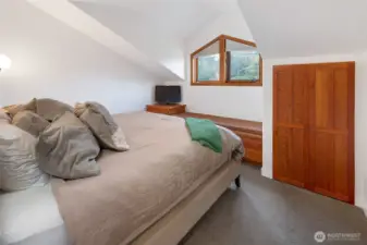 Inviting bedroom with soft natural light and built-in storage, offering a comfortable and private retreat tucked beneath vaulted lines.