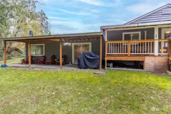 Back of home with patio and deck off primary bedroom