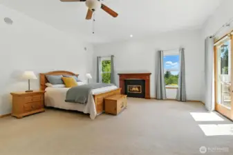 Primary Bedroom has a cozy fireplace, large windows and French doors leading to the deck