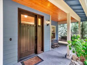Expansive covered wrap around front porch with a dramatic front door.