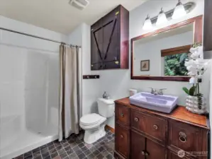 Primary bathroom includes slate tile floors and an eclectic sink vanity.