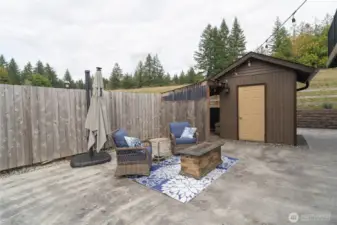 Back patio sitting area. Pump house equipped with sprinkler system! Plumbing/electrical present for hot tub hook-up. Woodshed or lawn storage area behind pump house.