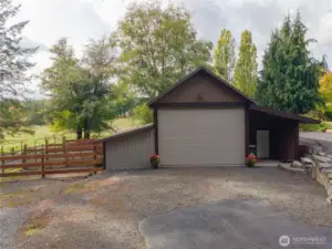 Front view of barn with large roll up door, as well as a covered patio area with man door.