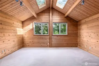 Primary bedroom on upper level, with plenty of light from large windows and two skylights.