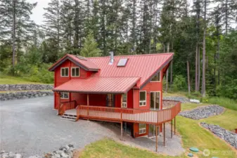 A wonderful view of the spacious driveway, and immaculate landscaping, with multiple rock terraces. The metal standing seam roof adds beauty and charm to this beautiful home.