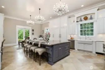 At the center of it all sits a stunning Shaws Lancaster 39.5” apron-front farmhouse sink, crafted in England, complete with Waterstone USA Rohl artisan fixtures, including a chrome pot filler, built-in soap dispenser, instant hot water tap, and hand sprayer. A trash compactor and built-in recycling bin make cleanup effortless. Surrounding the kitchen is a mix of diamond white quartzite countertops and a sprawling Cabernet quartz dining island—which comfortably seats four and includes an in-island sink for prepping fresh    vegetables from the garden. The island also boasts two Rev-a-Shelf appliance lifts, perfect for concealing a stand mixer or slow cooker, along with hidden outlets for added utility.