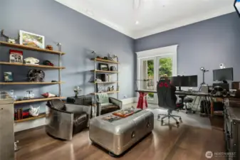 The main floor office offers replete with gray-washed Brazilian cherry wood floors, ornate trim and crown molding is a serene and inspiring environment designed for productivity and focus. French doors invite natural light to flood the room while framing picturesque views of the lush garden and majestic Mount Si beyond. Step out to the patio to breathe in the fresh mountain air, providing a perfect balance between work and relaxation. Inside, thoughtfully crafted rustic shelving lines the walls, offering ample space to showcase treasured collections, display artful décor, or house a curated library—creating both a functional workspace and a personal sanctuary. The home is wired with 1 Gig internet broadband, state-of-the-art ethernet cabling and automation linked to Alexa that can adjust the lighting, lock doors, even close the garage doors.