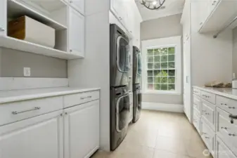 The spacious laundry room is equally impressive, equipped with dual stacked LG washer and dryer units, Italian marble countertops, an MTI sink with whirlpool jets made specifically for handwashing, a roll-out ironing board, roll-out shelves, built-in laundry hamper drawers, large hanging and folding spaces and two hidden rolling laundry carts that simplify laundry day. Ample storage throughout provides generous room for linens, extra bedding, pillows, toiletries, and towels—keeping everything neatly organized and within easy reach.