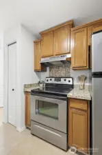 Stainless steel range and refrigerator pair with rich wood cabinetry and a decorative tile backsplash, offering both function and character.