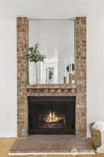 Full-height brick fireplace with mirror surround and mantel — a warm, standout feature in the living space.