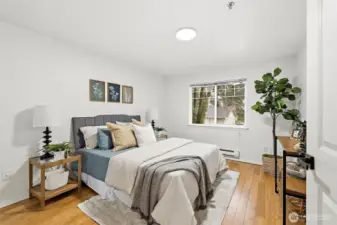 Comfortable bedroom with hardwood floors, a large window with treetop views, and plenty of space for a full furniture arrangement.