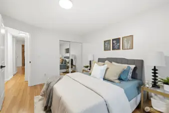 Well-sized bedroom featuring mirrored sliding closet doors and hardwood floors, with an open hallway connection to the rest of the unit.