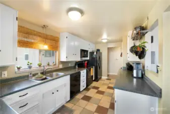 The quaint kitchen has lots of lovely cabinetry with decorative pulls and ceramic tile flooring